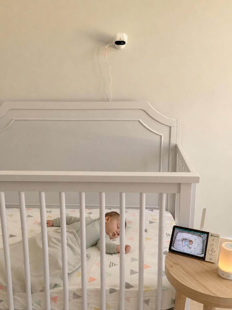A baby sleeping in a crib with the Nonnanest camera mounted above.