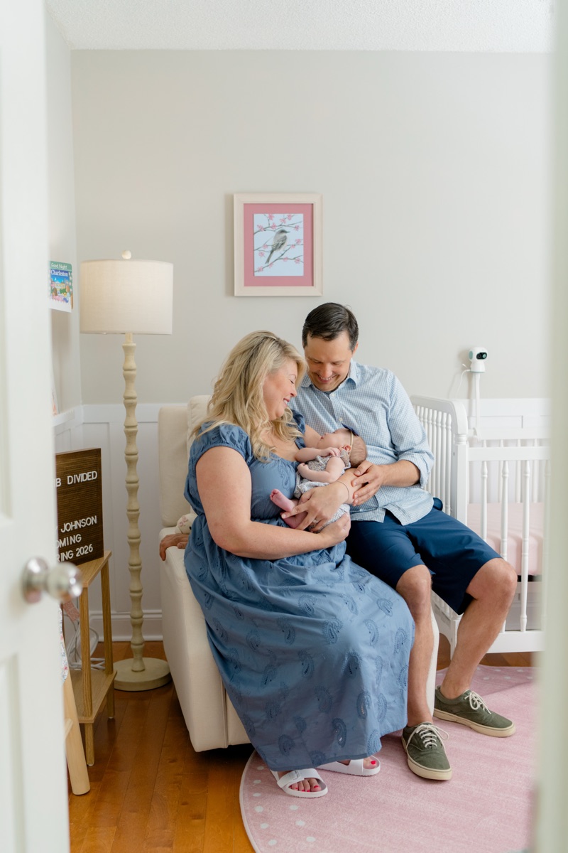A family holding their newborn in the nursery, with the Nonnanest camera set up on the crib behind them.